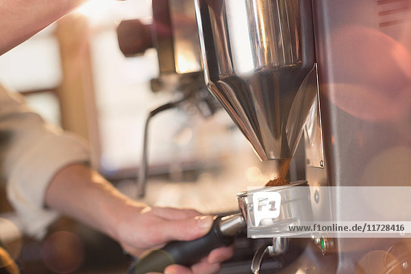 Close up barista using espresso machine grinder in cafe