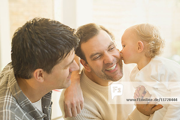 Zärtlicher Baby-Sohn,  der männliche schwule Eltern küsst.
