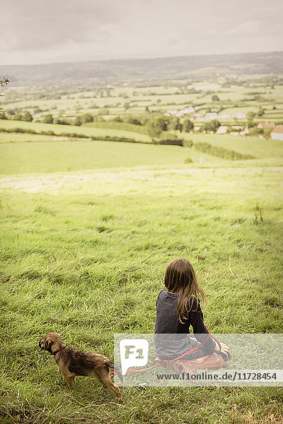 Mädchen mit Hundewelpe in ländlichem  grünem Feld auf dem Land