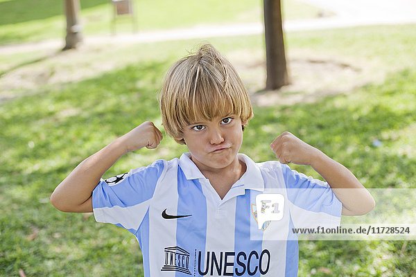 Verspielter blonder Junge im Park mit Fußball-T-Shirt