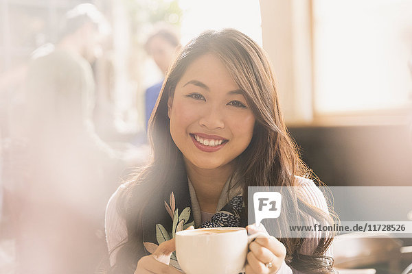 Portrait smiling Chinese woman drinking cappuccino in cafe