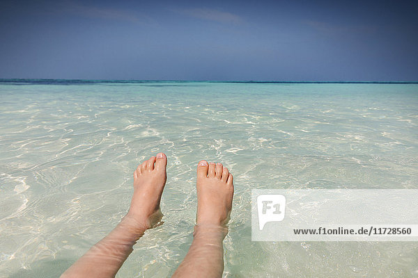 Persönliche Perspektive Barfuß Junge schwimmt in tropischen blauen Ozean