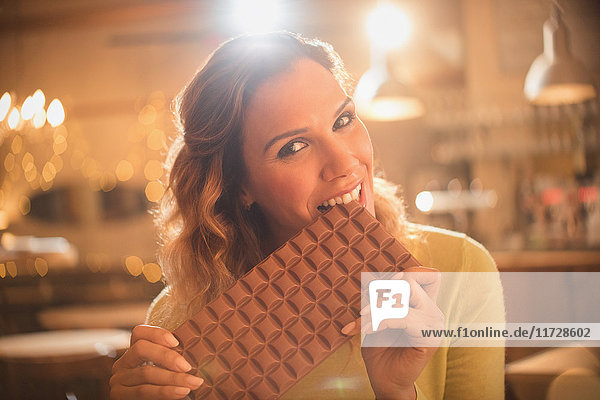 Portrait woman with sweet tooth craving biting into large chocolate bar