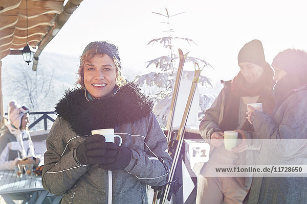 Portrait lächelnde Skifahrerin beim Kaffeetrinken auf dem Kabinendeck mit Freunden Apres-Ski