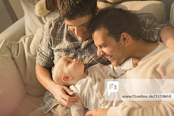 Blick von oben männliche schwule Eltern kuscheln mit süßem Baby-Sohn auf Sofa