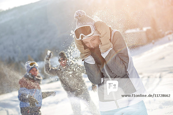 Verspielte Skifahrerfreunde genießen Schneeballschlacht im verschneiten Gelände