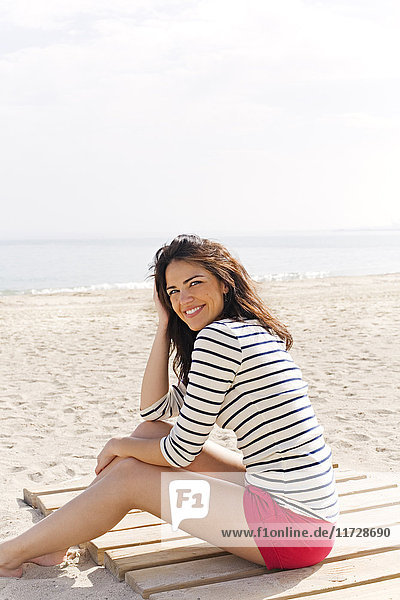 Portrait of a beautiful brunette woman sitting at the beach