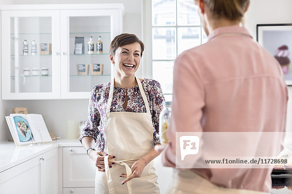 Lächelnde Catererinnen binden Schürzen in der Küche