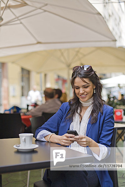 Hübsche brünette Frau mit Smartphone im Cafe