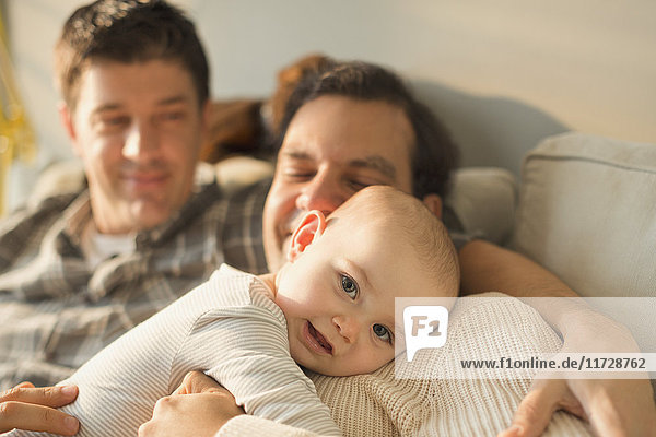 Portrait cute baby son cuddling with male gay parents