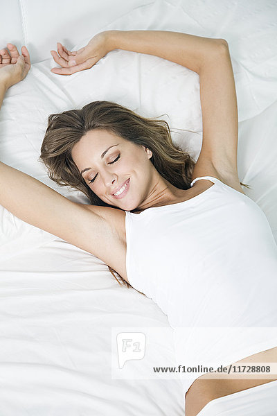Portrait of a blonde woman waking up stretching in bed