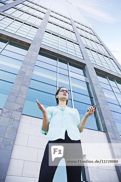 Geschäftsfrau mit Stress beim Telefonieren vor einem Gebäude