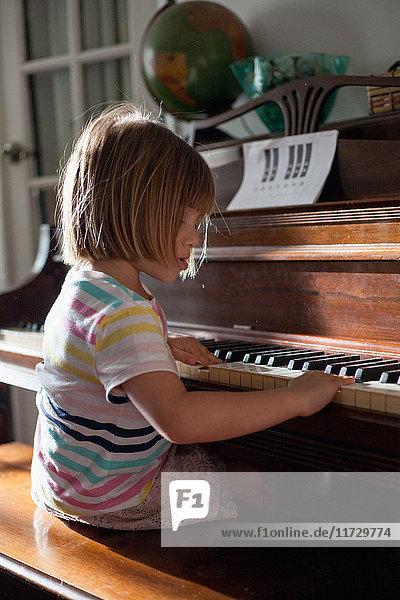 Girl at home playing old piano