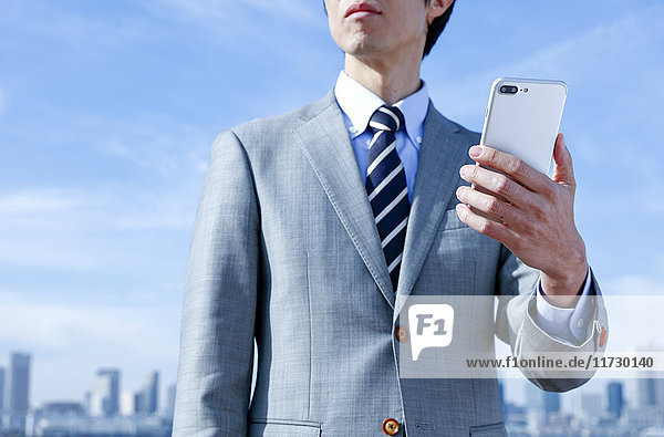 Japanischer Geschäftsmann mit Smartphone in der Innenstadt von Tokio  Japan
