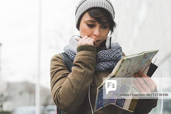 Female backpacker biting nails and looking at map in city