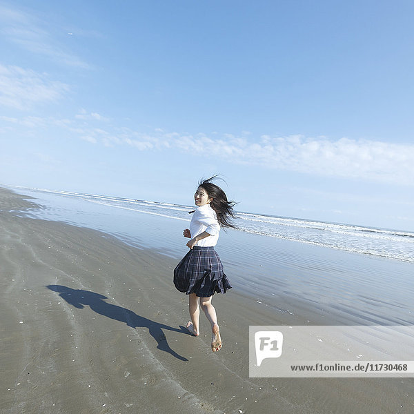 Junge Japanerin in Highschool-Uniform beim Laufen am Meer  Chiba  Japan