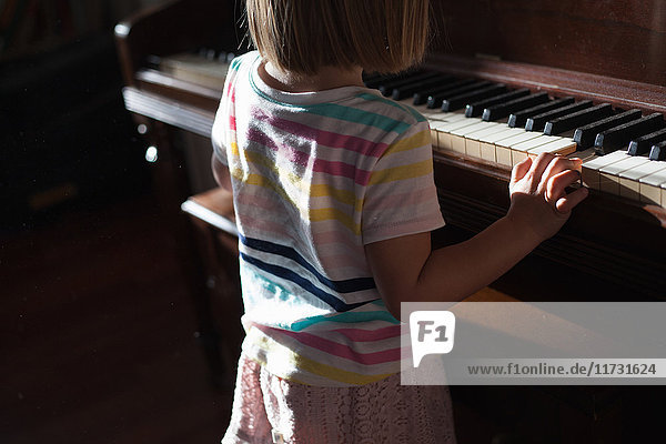 Ansicht des hinteren Mittelteils eines Mädchens  das zu Hause altes Klavier spielt