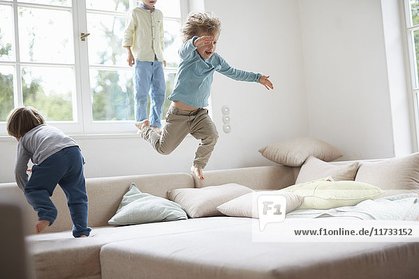Drei kleine Jungen springen auf dem Sofa