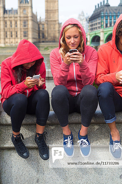 Drei junge Leute schauen auf Mobiltelefone