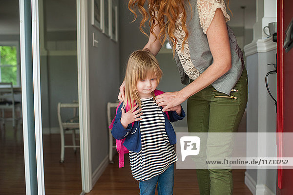 Mutter hilft Tochter beim Anlegen des Rucksacks