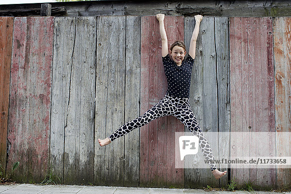 Teenage girl hanging from wooden fence
