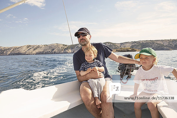 Mature man steering motor boat with sons  Lopar  Rab Island  Croatia