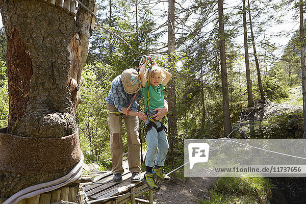 Vater und Kind bereiten sich im Wald auf das Hochseil vor  Ehrwald  Tirol  Österreich