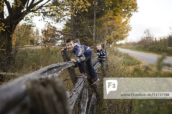 Boys climbing over fence looking at camera smiling