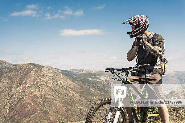 Downhill-Mountainbiker setzen Helm auf