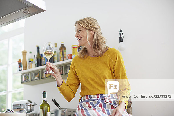 Frau hält Weinglas in der Küche hoch