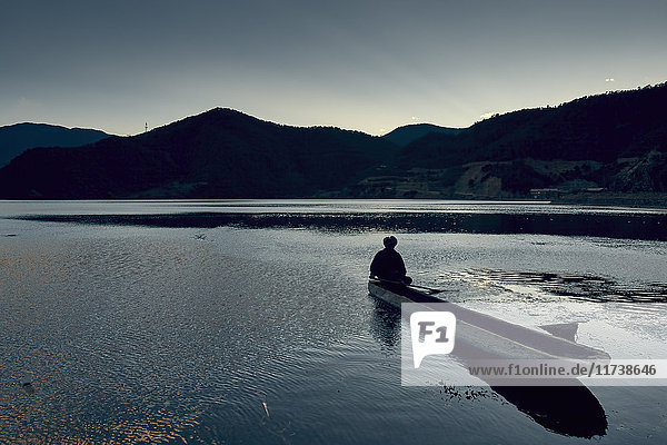 Silhouette of mountain range with man in boat  Luga Lake  Yunnan  China