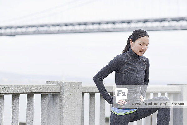 Female runner stretching on bridge  San Francisco  California