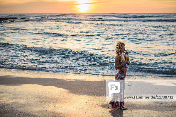 Portrait of young woman drinking cocktail on beach at sunset  Tamarindo  Costa Rica