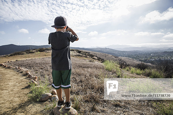 Rear view of boy looking through binoculars from footpath stone  Thousand Oaks  California USA