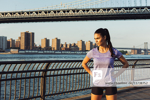 Young female runner looking out in front of Manhattan bridge  New York  USA