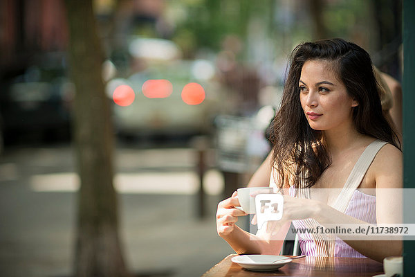 Mittelgroße erwachsene Frauen trinken Kaffee in Straßencafé