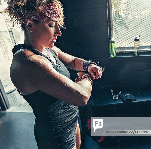 Woman fastening wrist strengthener in gym