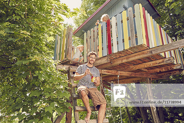 Portrait of father and two sons painting tree house