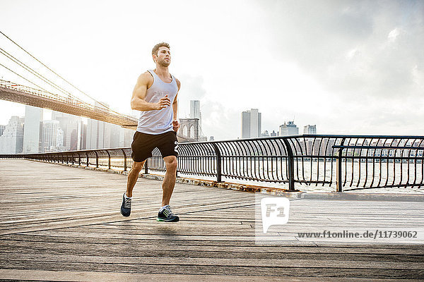 Young male runner running along riverside  Brooklyn  New York  USA