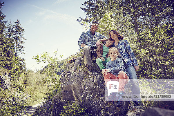 Porträt einer Familie  die auf einem Felsen im Wald sitzt
