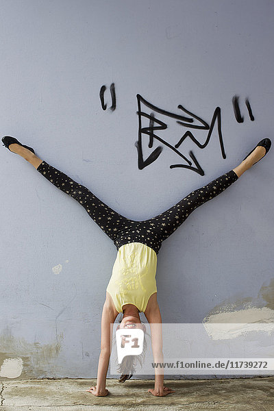 Teenage girl doing handstand against wall