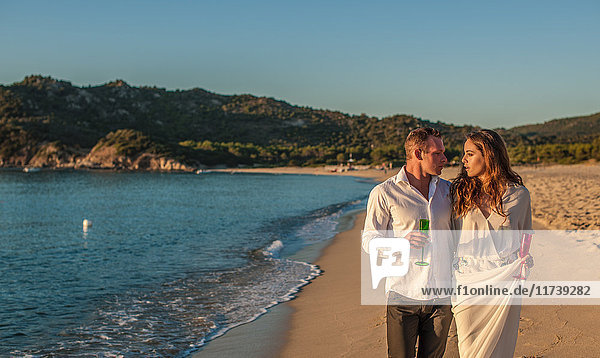 Junges Paar schlendert mit Champagner am Strand  Castiadas  Sardinien  Italien