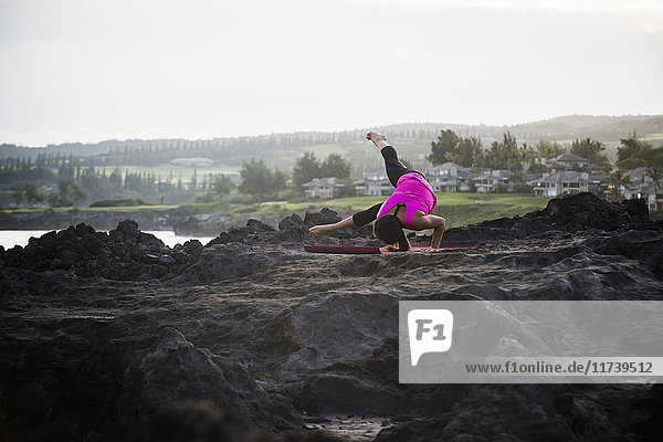 Frau an der Küste praktiziert Yoga-Balancieren auf Händen  Hawea Point  Maui  Hawaii  USA