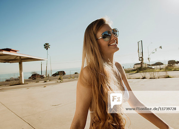 Junge Frau mit Bikinioberteil und Sonnenbrille  lächelnd