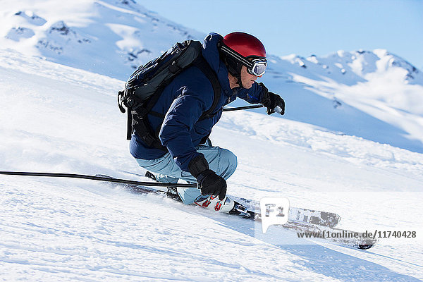 Männlicher Skifahrer rast den Berg hinunter
