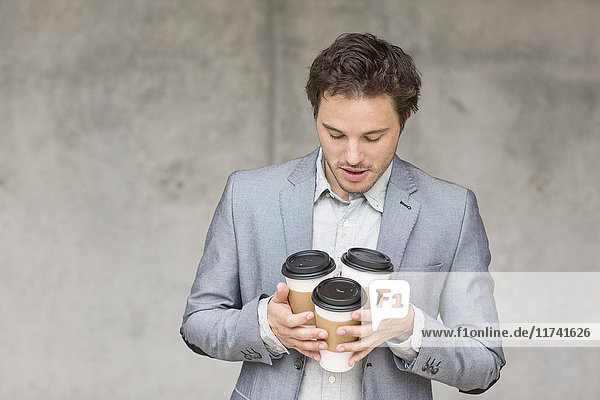 Geschäftsmann mit Einweg-Kaffeetassen