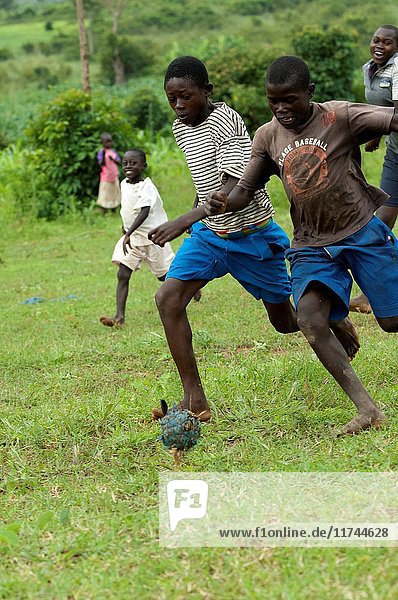 Barefooted teenagers playing football with a homemade ball on a grass field  Kenya. (Photo by: Wayne Hutchinson/Farm Images/UIG)