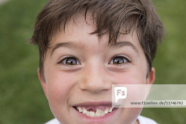 Porträt eines Jungen  der lächelt und eine Lücke von einem verlorenen Zahn zeigt