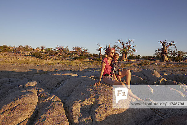 Mother and son sitting on rock  looking at view  Gweta  makgadikgadi  Botswana