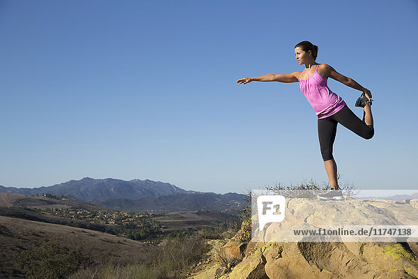 Mature woman practicing yoga tree pose on top of hill  Thousand Oaks  California  USA